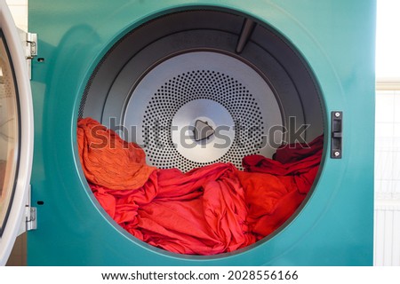 Tumble dryer. Centrifuge for drying linen and clothes. Laundry. Washer. Washing linen. The centrifuge spins and washes laundry and clothes. The laundry is open. Linen in bright red colors.