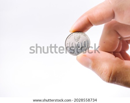 a man's hand showing coins on a white background.  The coins used are coins from the Indonesian state in the thousand rupiah denomination.  photo taken in West Java Indonesia on August 21, 2021