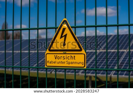 High voltage warning sign with German Text "Hochspannung Lebensgefahr". Warning sign on the fence of a solar power plant.