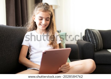 Portrait of a happy teenage girl using digital tablet in home.