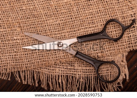 Small scissors on a piece of homespun fabric with a rough texture