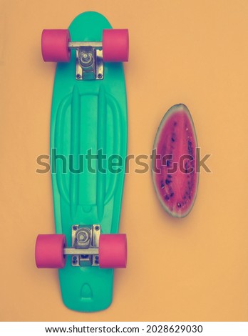 Slice of ripe watermelon and cruiser board on a yellow background. Summer fun. Top view