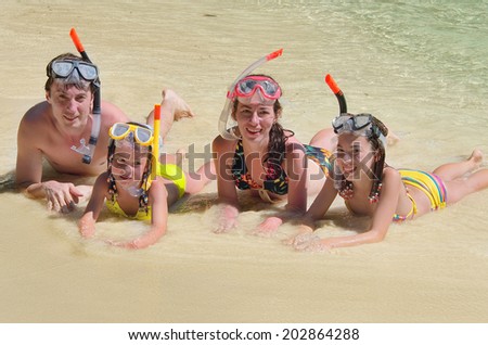 Happy family in snorkels on tropical beach having fun on sea vacation 