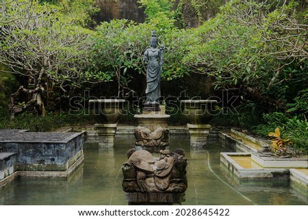 four turtle-shaped fountains and a teal marble statue in a pond, surrounded by plants
