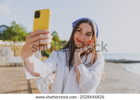 Close up young cool traveler woman in bandana shirt summer clothes do selfie shot mobile cell phone post photo social network outdoor at sea beach background People vacation lifestyle journey concept