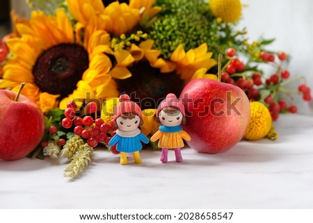 Cute little dolls, apples and autumn flowers close up. beautiful fall seasonal composition. autumn time concept. 