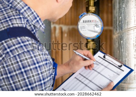 Technician With Clipboard Reading Water Meter Or Counter Royalty-Free Stock Photo #2028662462