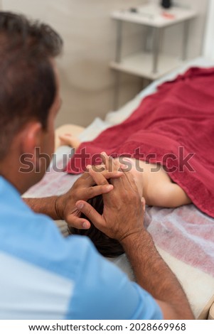 Wellness massage for children. Hands of the masseur close-up. Physiotherapist working with patient in clinic. Vertical photo