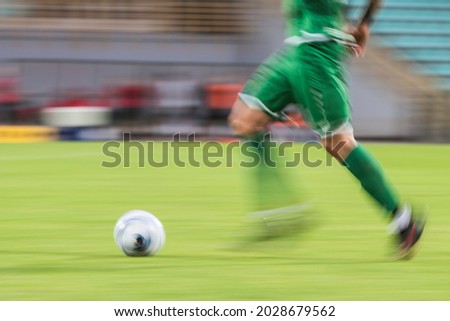 Football player runs with ball during match - blurred motion due to long exposure
