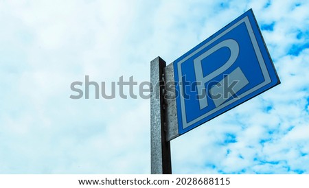Blue road sign with letter P on rectangular plate isolated against a blue sky. Parking symbol on a cloudy blue sky background.