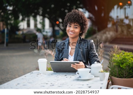 Latin businesswoman drinking coffee. Smiling businesswoman networking wiht tablet and cellphone