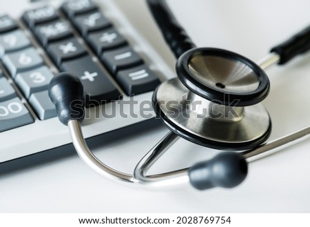 Closeup of a calculator and a stethoscope healthcare and expenses concept