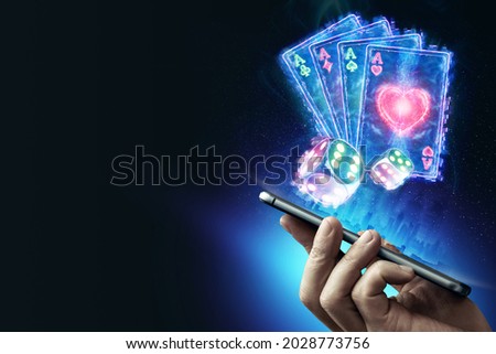 Creative background, online casino, in the male hand a smartphone with playing neon cards, neon background. Internet gambling concept. Copy space. Royalty-Free Stock Photo #2028773756
