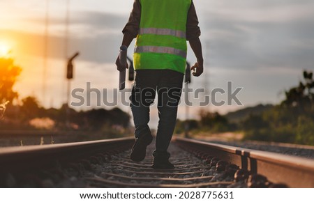 Back side view engineer under inspection and checking construction process railway switch and checking work on railroad station .Engineer wearing safety uniform and safety helmet in work. Royalty-Free Stock Photo #2028775631