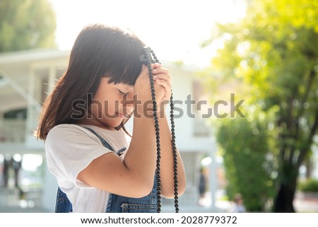 Little Asian girl praying with holding the cross, Christian concept. 