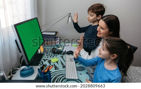 Mother and children waving on video call with computer