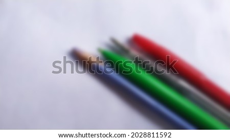 Blurred abstract background of stationery markers, pens and pencils on a white background.