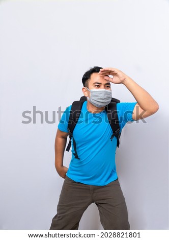 a man with black backpack wears medical mask and a cloth mask to protect from the covid-19 virus. looking for something