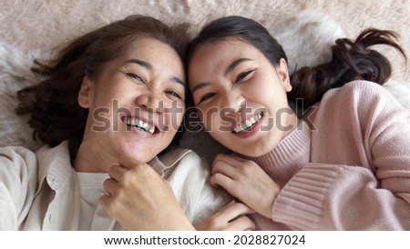 POV attractive beautiful two people asia young lady girl use mobile phone take photo picture video overjoy lying down at home floor have good time day together quarantine in mum healthy health care.