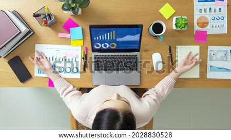 Above top view of asia girl work on desk table home office sit calm inhale deep stress relief in zen lotus yoga post. Good break rest time for teen labor people serene life in job career workforce. Royalty-Free Stock Photo #2028830528