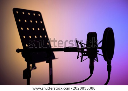 Voiceover studio large diaphragm cardioid microphone, headphones and lectern in professional voice recording studios.