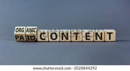 Paid or organic content symbol. Turned wooden cubes and changed words 'paid content' to 'organic content'. Beautiful grey table, grey background, copy space. Business, paid or organic content concept. Royalty-Free Stock Photo #2028844292