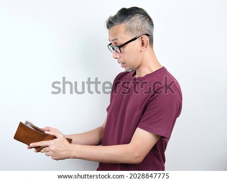 Shocked face of Asian man and hand open empty wallet no money.
