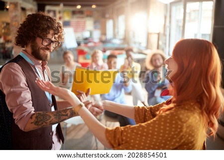 young redhead female congratulate to a caucasian business student after successful attending seminar, giving him certificate in folder. selective focus image.