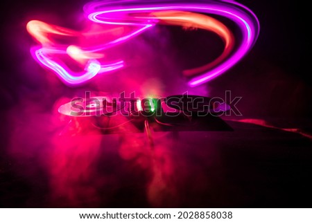 Dj club concept. Creative artwork decoration of dj table on dark toned background with lights and fog. Selective focus