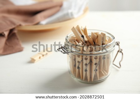 Many wooden clothespins in glass jar on white table, space for text Royalty-Free Stock Photo #2028872501