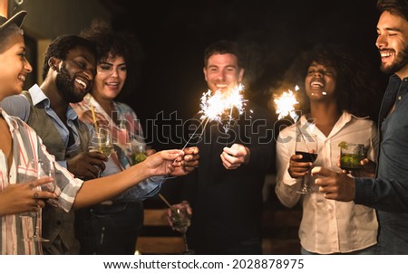 Happy young friends having fun with sparklers fireworks and drinking cocktails on house patio party - Youth people lifestyle and holidays concept Royalty-Free Stock Photo #2028878975