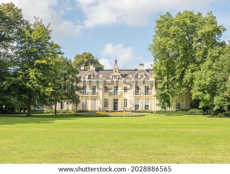 17th century monumental mansion with a lawn, trees and blue sky with white clouds Royalty-Free Stock Photo #2028886565