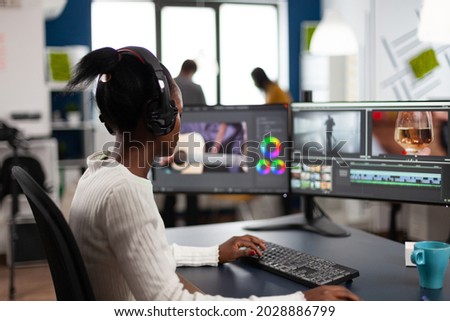 Black woman editor working at project film montage sitting in modern creative agency office. Videographer in digital multimedia company editing movie with post production software