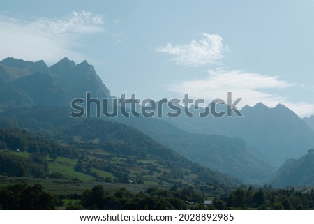 Layered mountain landscape backlit by sun on distance with haze. Lescun, Pyrenees mountains, France.