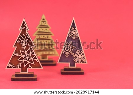 Creative wooden christmas trees on red background. Focused on the front fir.Merry christmas happy new year, winter holidays concept.