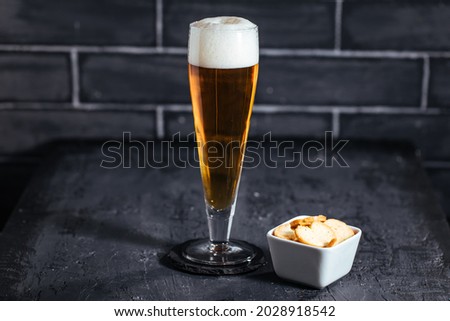 Glass of beer on dark background with crackers