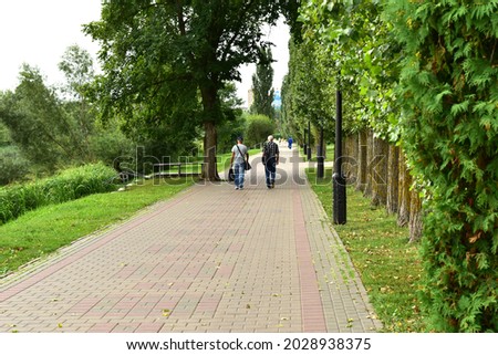 A man and a woman walk along the path of the city park.