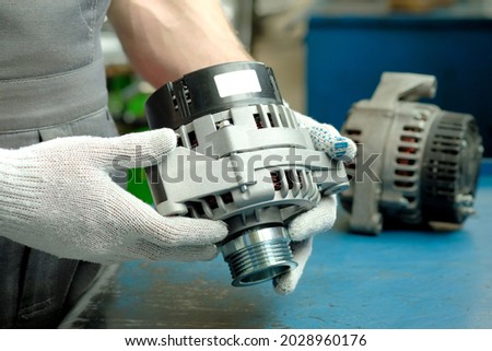 Spare parts for the car.An auto mechanic holds a new generator in his hands.Replacement of a faulty electrical unit in the power plant of the car. Royalty-Free Stock Photo #2028960176