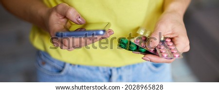 Banner of Unrecognizable woman with blister pack of pills and smartphone in hand using online pharmacy store, buying pharmacy on internet, ordering medicine online at home in sunny day. Copy space.