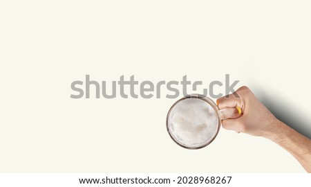 Man Hand Holding Mug Full Of Beer On White Background. Isolated top up view. Royalty-Free Stock Photo #2028968267