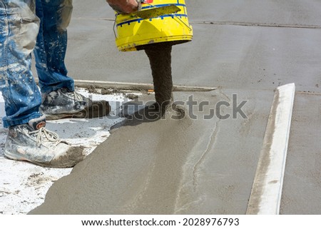 Worker Spreading Building Screed on a Floor of a House during Energy Redevelopment Work on Blurred Background Royalty-Free Stock Photo #2028976793