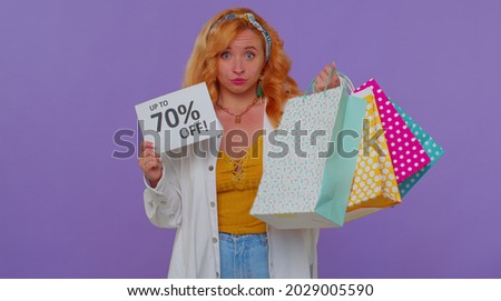 Cheerful long haired girl showing shopping bags, Up To 70 Percent Off inscriptions banner text. Black Friday. Good holiday discounts, low prices for shopping. Young woman posing on purple background