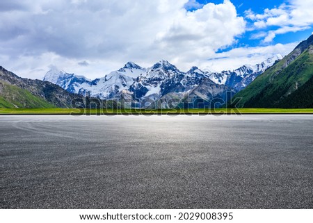 Empty asphalt road and white snow mountain natural scenery.
