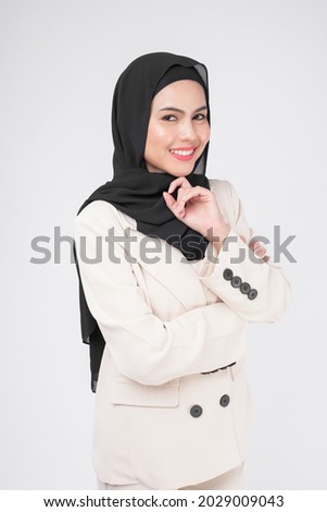 Portrait of young smiling muslim businesswoman wearing suit with hijab over white background studio.	