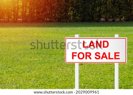 Land for sale. Land for sale sign on green grass. Purchase of site plot. Purchase of empty land. Purchase of site for construction of house. Sign advertising ground on clipped grass background