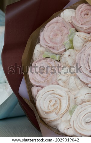 Marshmallow bouquets in craft packaging. Consist of marshmallow roses and tulips. The bouquets lie on the table surface. Close-up shot.