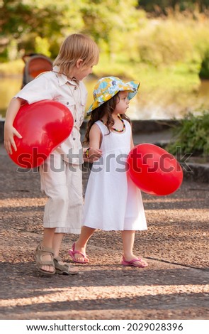 Little girl and boy with balloons in the park