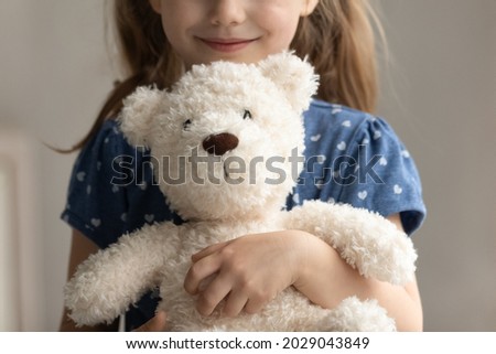Close up of teddy bear in arms of child. Happy smiling little girl kid holding, hugging toy, playing with plush soft friend. Cropped portrait. Childhood, preschooler, playtime, childcare concept Royalty-Free Stock Photo #2029043849