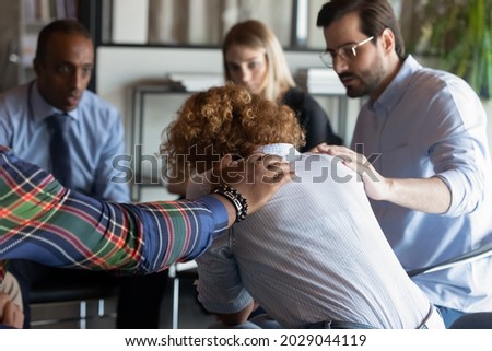 Supportive multiracial employees comfort caress unhappy upset female colleague coworker at team meeting. Caring loving diverse multiethnic people support distressed woman at group gathering. Royalty-Free Stock Photo #2029044119