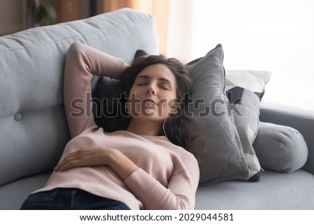 Peaceful woman closed her eyes take break lying sleeping on comfy couch having day nap resting alone in living room, breath fresh conditioned air, reduce fatigue, relish day off at modern home concept Royalty-Free Stock Photo #2029044581